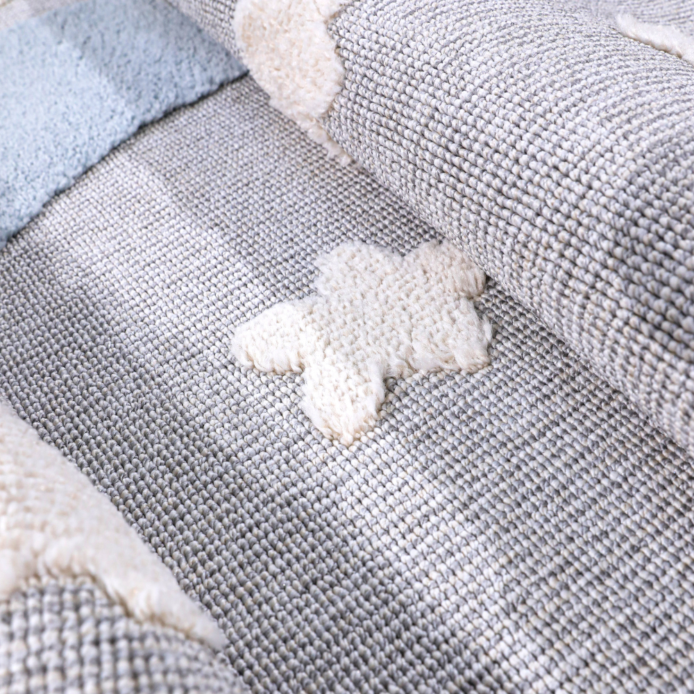 Kids woven rug with textured star and moon designs in soft gray and blue tones.