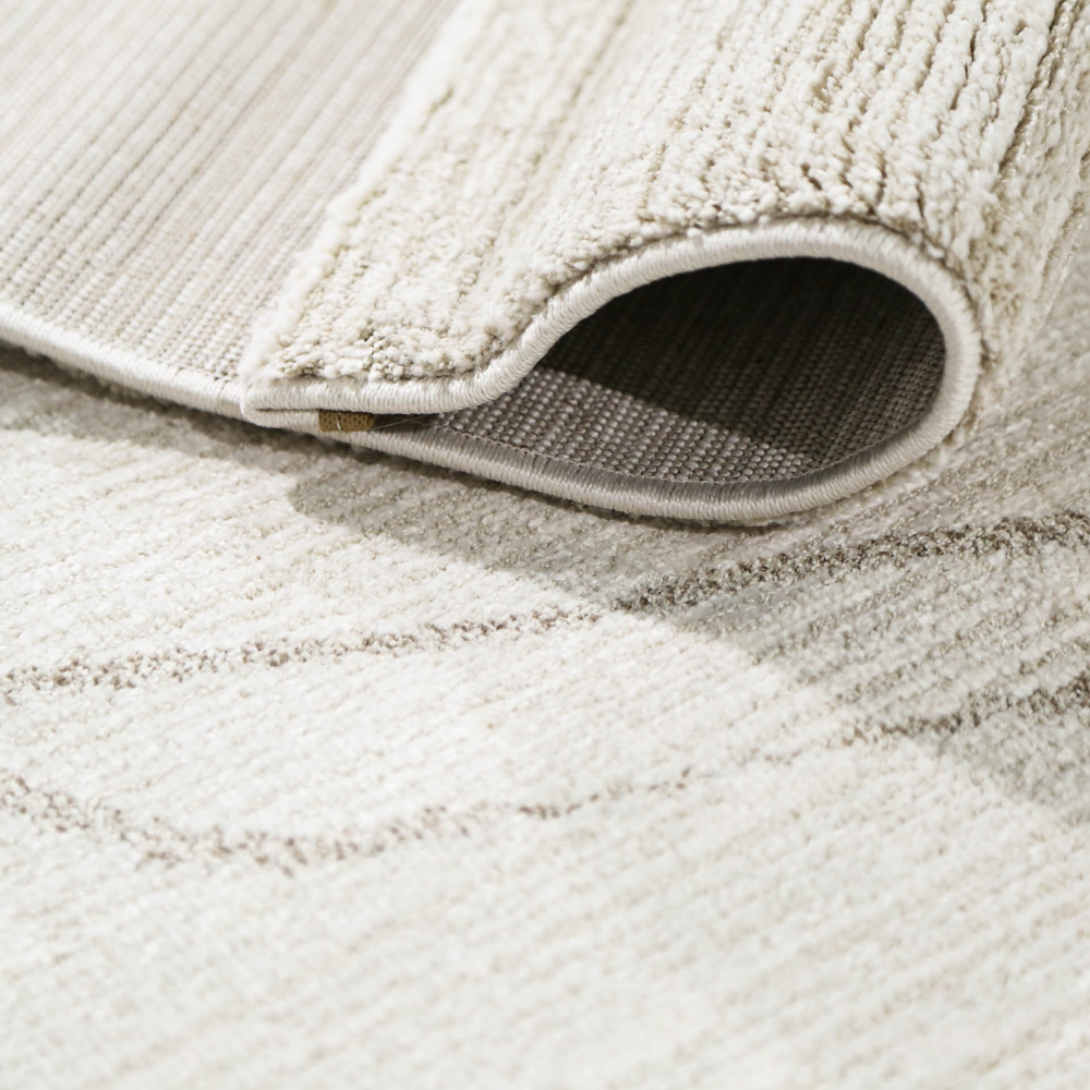 Thalion abstract textured rug in neutral tones with rolled edge, perfect for modern decor.