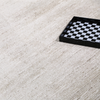 Romulus textured rug in light color with checkerboard tray, ideal for modern interiors.